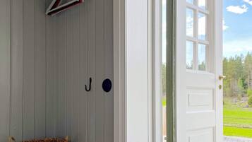 A room with a white door, a hanging coat rack, and a woven basket.