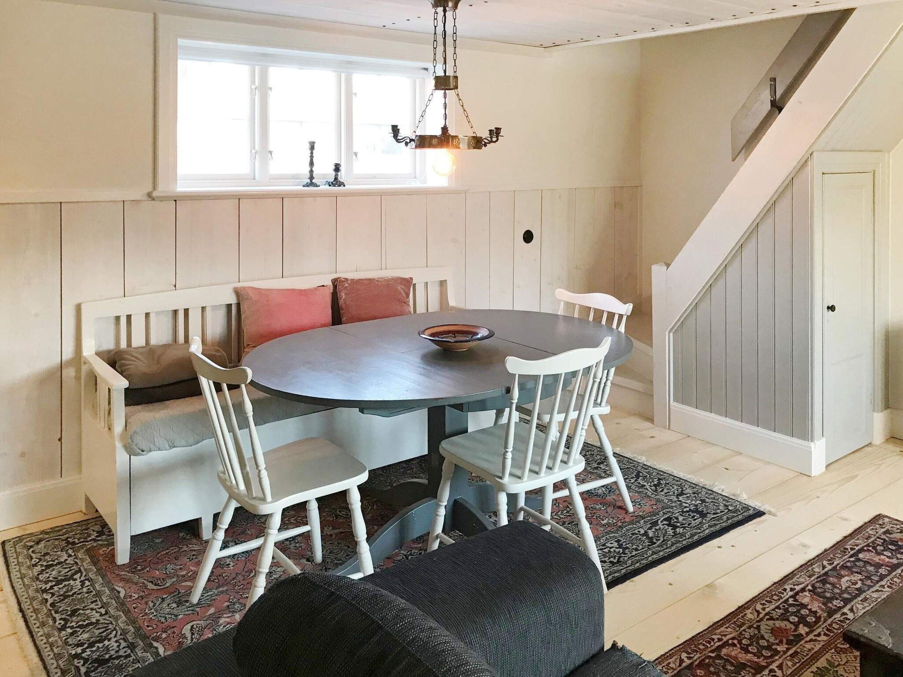 A dining area with a round table, white chairs, and a bench with cushions.