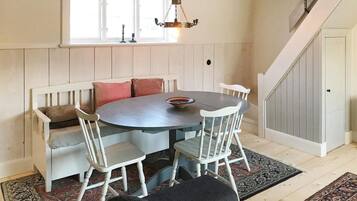 A dining area with a round table, white chairs, and a bench with cushions.