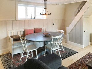 A dining area with a round table, white chairs, and a bench with cushions.