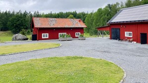 Une grange rouge avec une allée en gravier et un petit jardin.