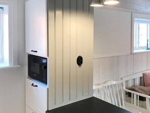 A room with a white cabinet, a black microwave, and a white crib with a pink pillow. - 4 Star Holiday Home in Mellosa (Flen)