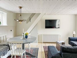 Una sala moderna con comedor, una escalera y un televisor de pantalla plana montado en la pared.