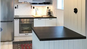Une cuisine moderne avec des meubles blancs, des appareils en acier inoxydable et un plan de travail noir.