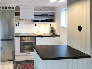A modern kitchen with white cabinetry, stainless steel appliances, and a black countertop. - 4 Star Holiday Home in Mellosa (Flen)