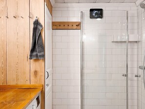 A bathroom with a wooden vanity, a towel rack, a shower with a glass door, and a small mirror. - 4 Star Holiday Home in Mellosa (Flen)