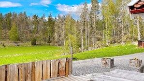 Une terrasse en bois offrant une vue sur un champ verdoyant et une forêt.