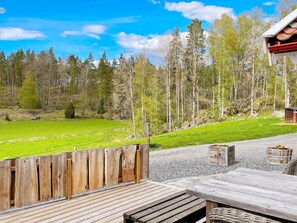 A wooden deck with a view of a green field and forest. - 4 Star Holiday Home in Mellosa (Flen)