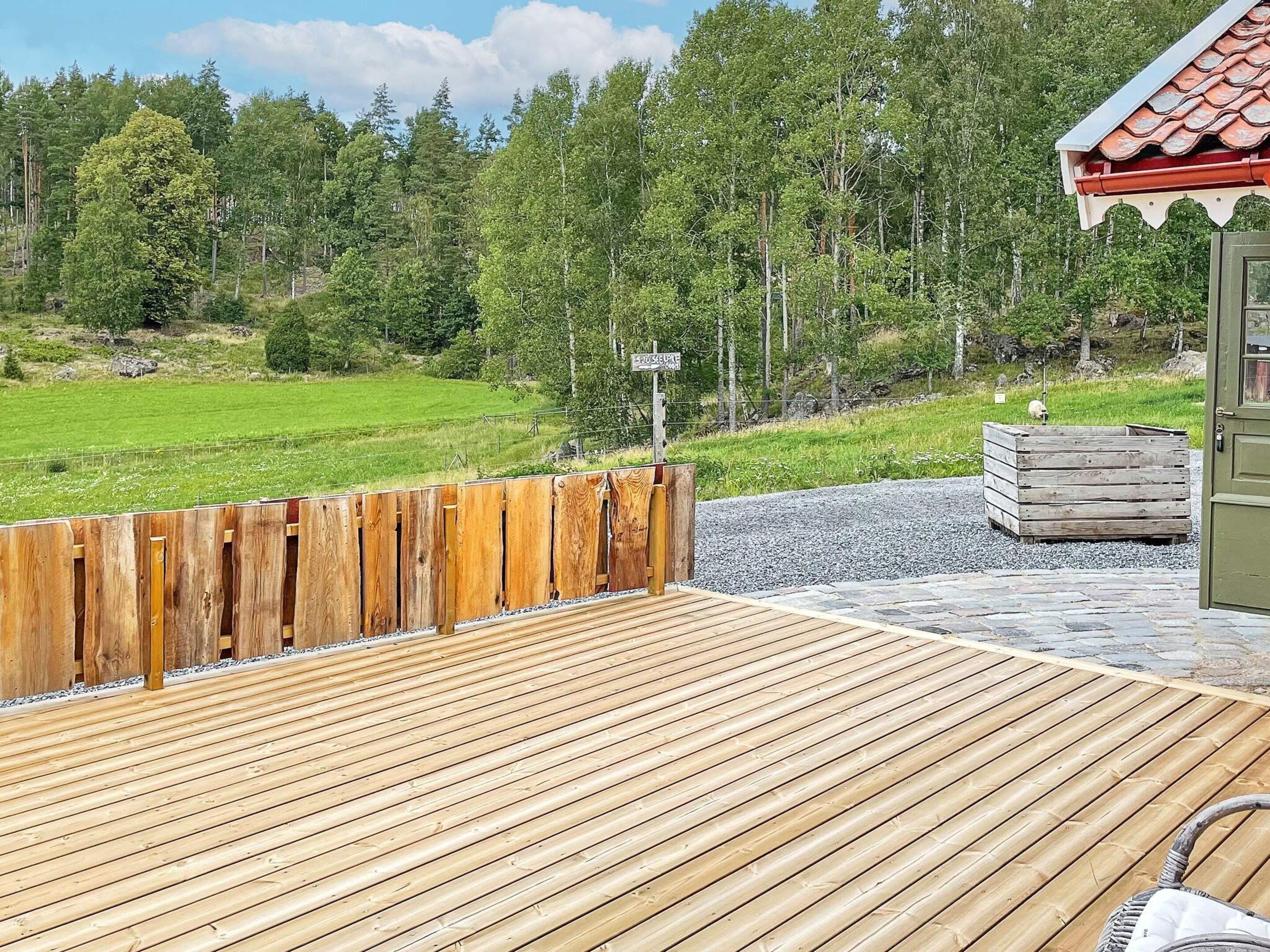 Een houten terras met uitzicht op een groen veld en bomen.