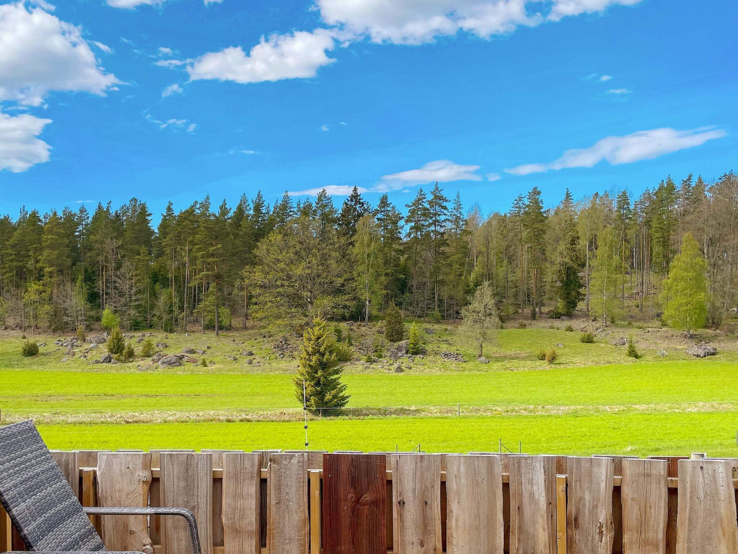 Eine Holzterrasse mit Blick auf einen Wald und ein grünes Feld.