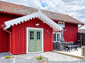A red building with a green door, a white porch, and outdoor seating. - 4 Star Holiday Home in Mellosa (Flen)