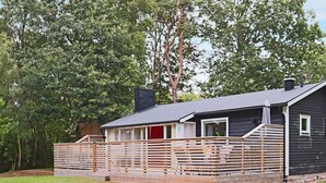 En liten stuga i ett våningsplan med en veranda, omgiven av träd.