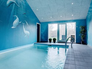 An indoor swimming pool with a blue wall mural, a clear view outside, and a potted plant. - 5 Star Holiday Home in Vejby (Vejby)