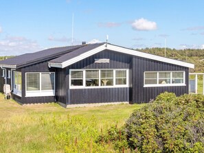 A single-story building with a dark exterior, large windows, and a flat roof. - 4 Person Holiday Home in Lokken (Lokken)