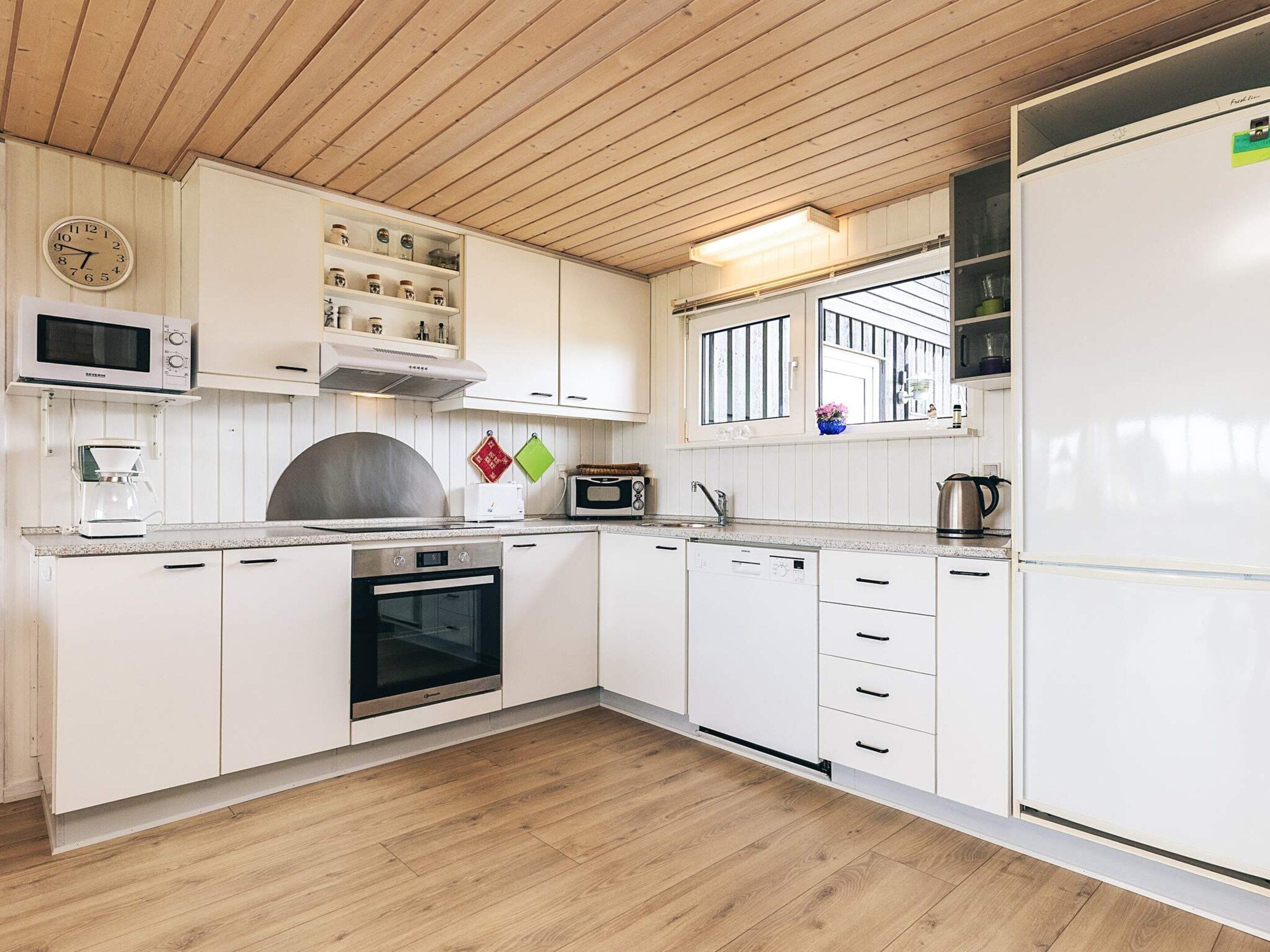 Una cucina moderna con mobili bianchi, un forno a microonde, una macchina da caffè, un tostapane e una lavastoviglie.