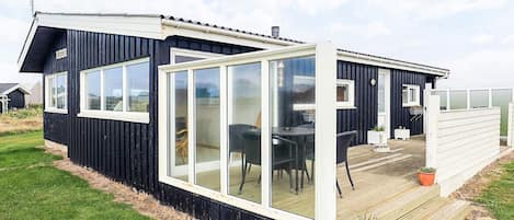 A modern house with a large glass door, a deck, and a small garden area.