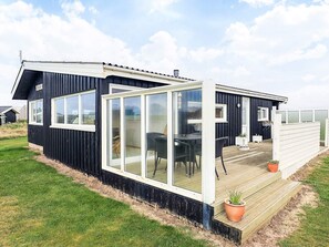 A modern house with a large glass door, a deck, and a small garden area.