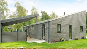 A modern two-story house with a covered porch, a well-maintained lawn, and a wooden fence.
