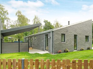 Une maison moderne à deux étages, dotée d’un porche abrité, d’une pelouse bien entretenue et d’une clôture en bois.