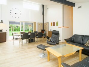 Un salon moderne avec une table basse en verre, un canapé en cuir et un coin repas avec des chaises.
