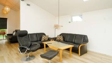 A modern living room with a leather sofa, a glass coffee table, and a leather chair.