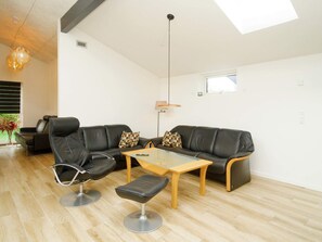 A modern living room with a leather sofa, a glass coffee table, and a leather chair. - 5 Star Holiday Home in Vig (Vig)