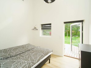A bedroom with a bed, a window with blinds, a door leading outside, and a small wall-mounted hanger.