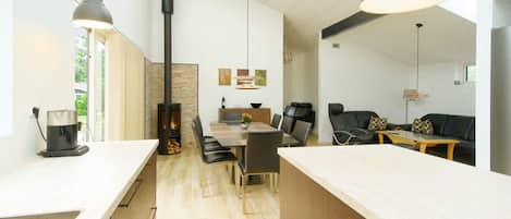 A modern kitchen with a central island, dining area with chairs, and a living space with a sofa and coffee table.