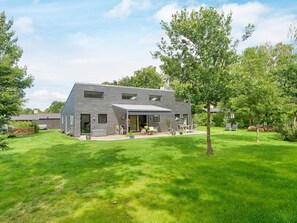 A modern two-story house with a covered patio, surrounded by a well-maintained lawn and trees. - 5 Star Holiday Home in Vig (Vig)