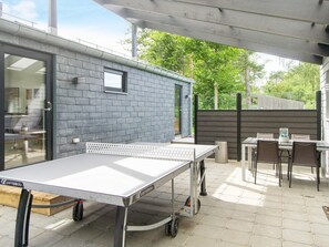 An outdoor patio with a ping pong table, a dining table, and chairs. - 5 Star Holiday Home in Vig (Vig)