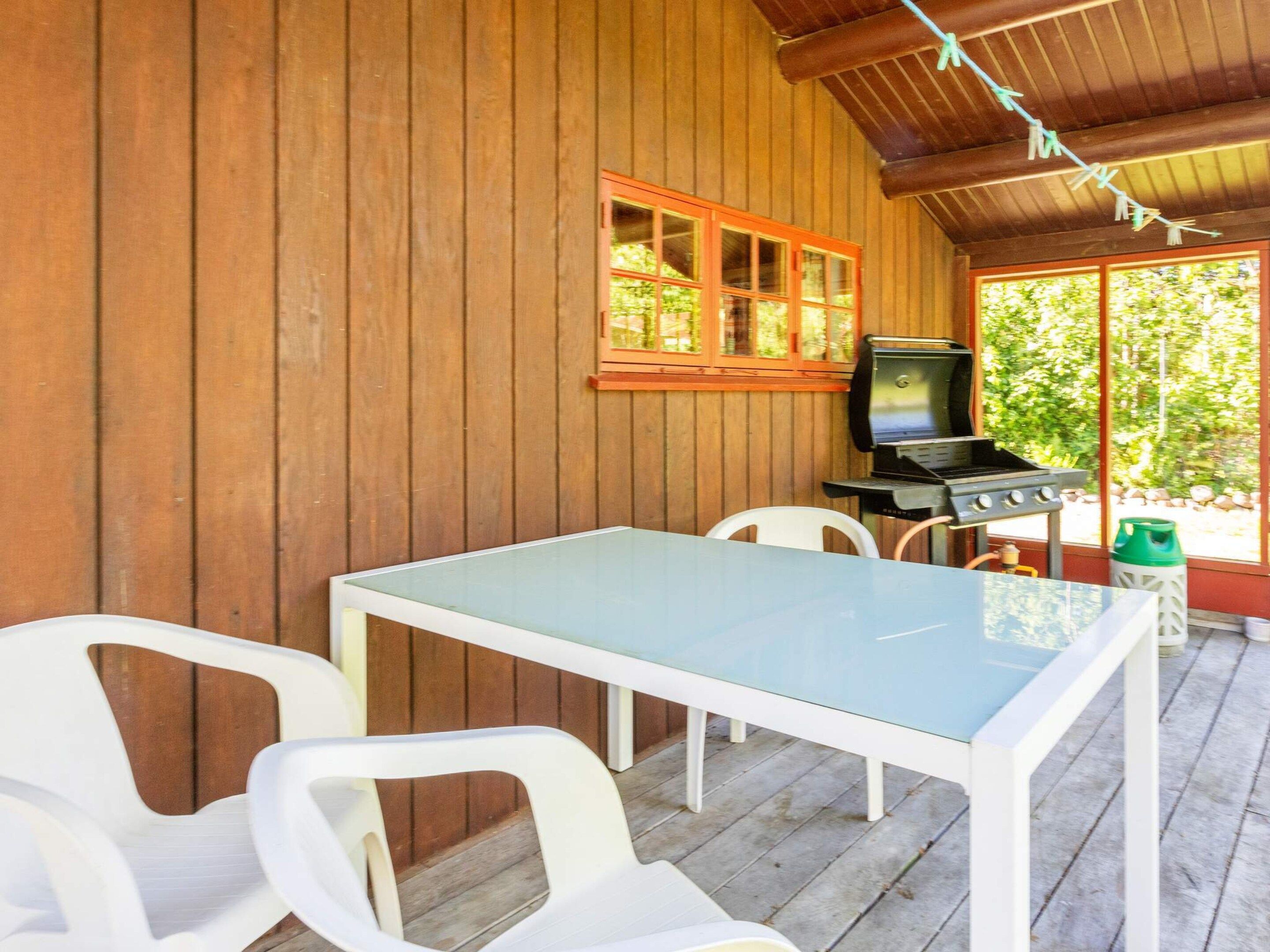 A covered outdoor area with a table and chairs, a television, and a grill.