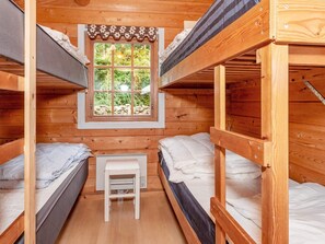 A compact room with two bunk beds, a small white table, and a window with a view of greenery. - 6 Person Holiday Home in Roslev (Roslev)