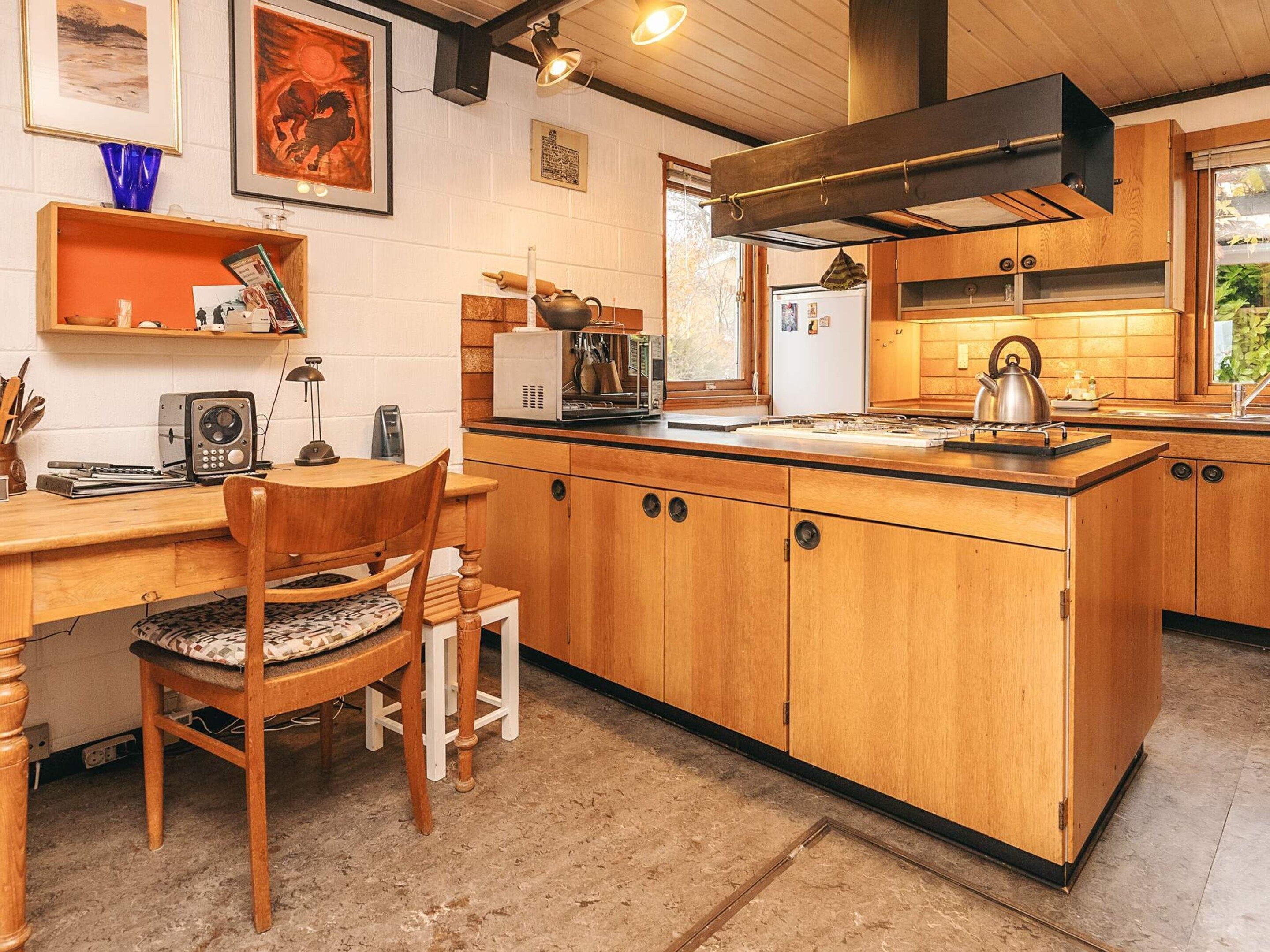 A compact kitchen with wooden cabinets, a central island, a built-in stove, and a window providing natural light.