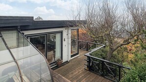 A modern house with a wooden deck, large glass windows, and a view of trees and sky. - 5 Person Holiday Home in Hesselager (Hesselager)