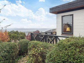 A modern building with a large window, a balcony with a railing, and a view of the sea. - 5 Person Holiday Home in Hesselager (Hesselager)