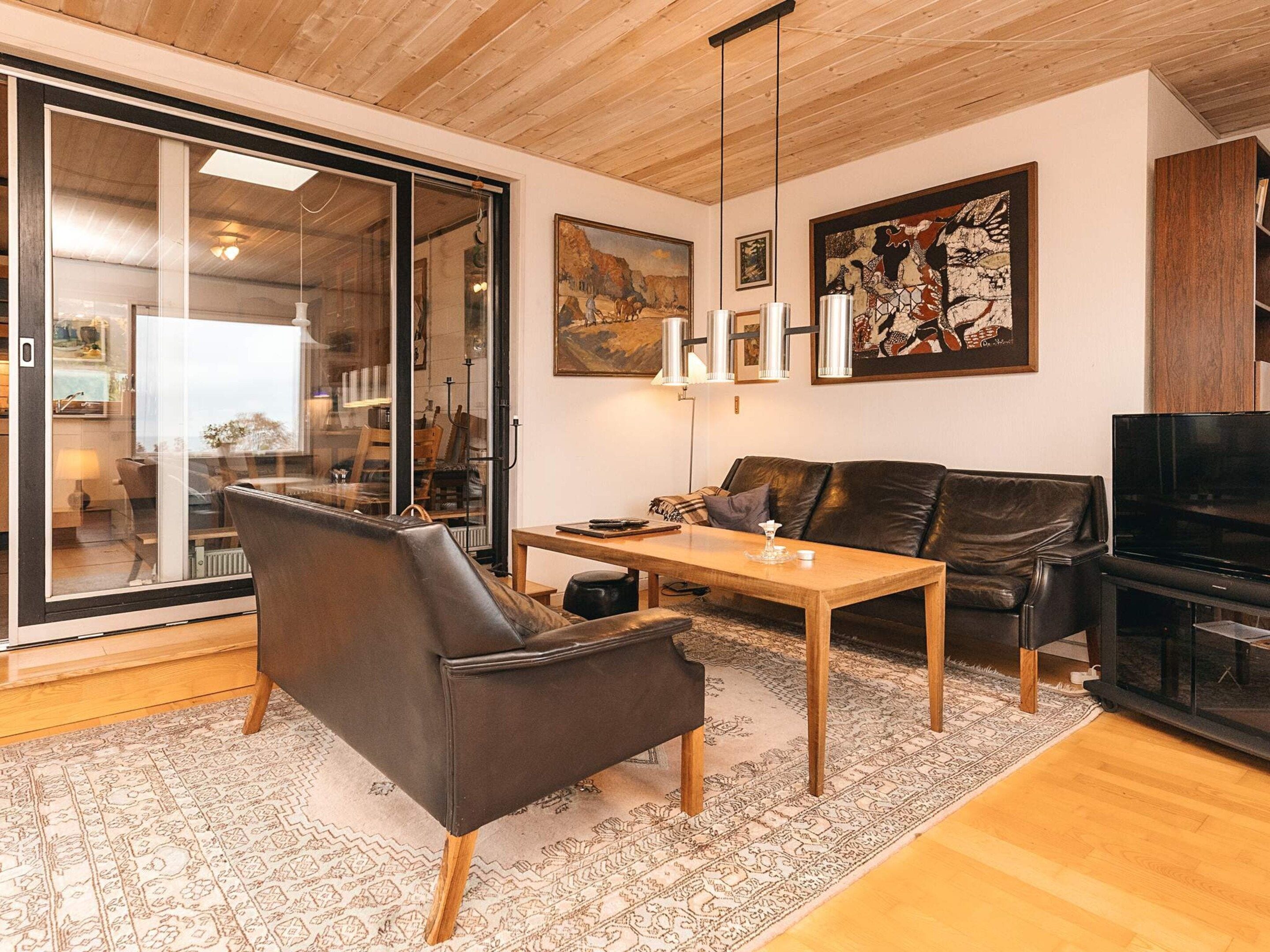 A modern living room with a leather sofa, a wooden coffee table, and a television.