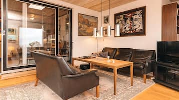A modern living room with a leather sofa, a wooden coffee table, and a television.