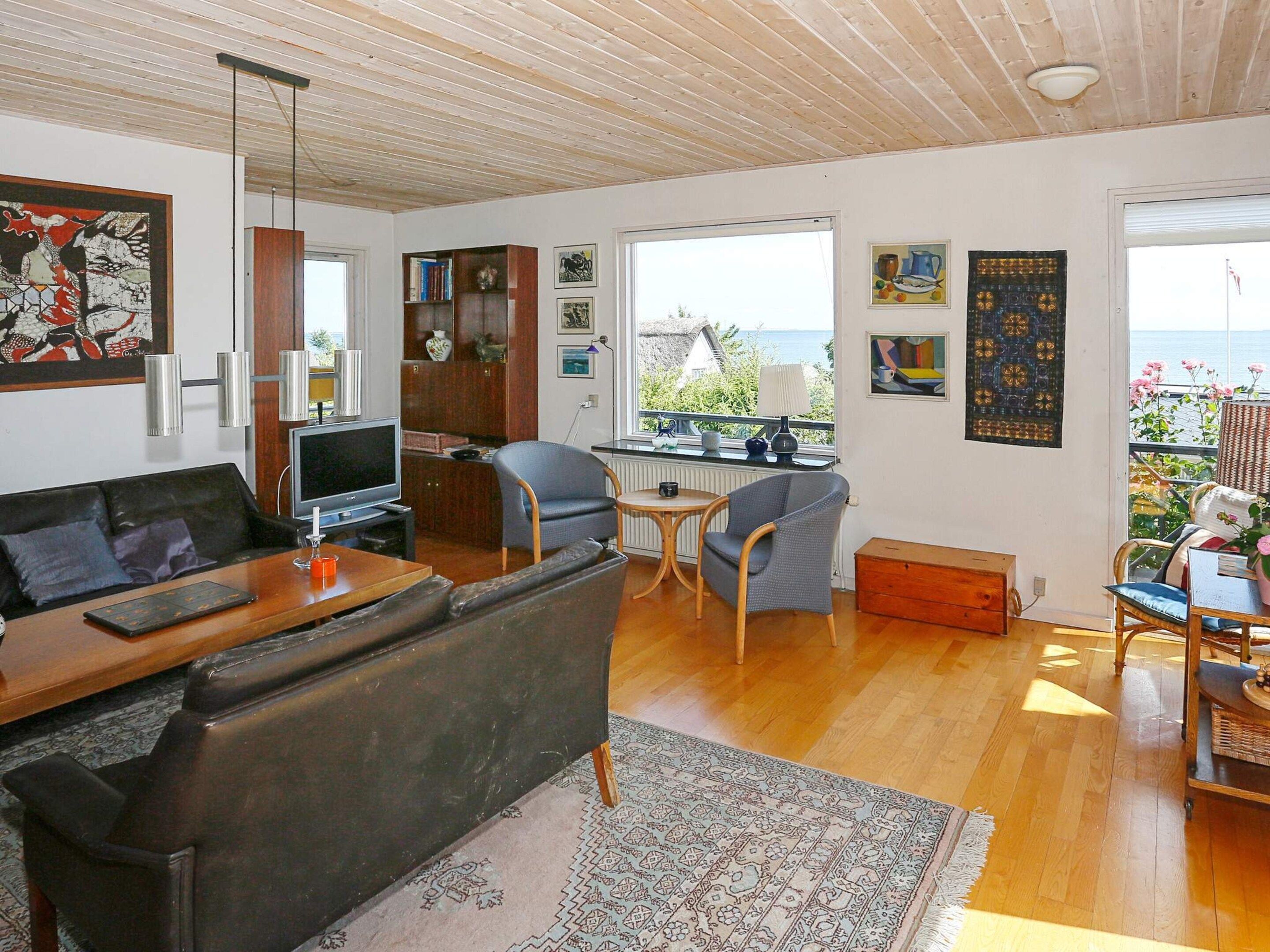 A living room with a sofa, TV, and a view of the sea.