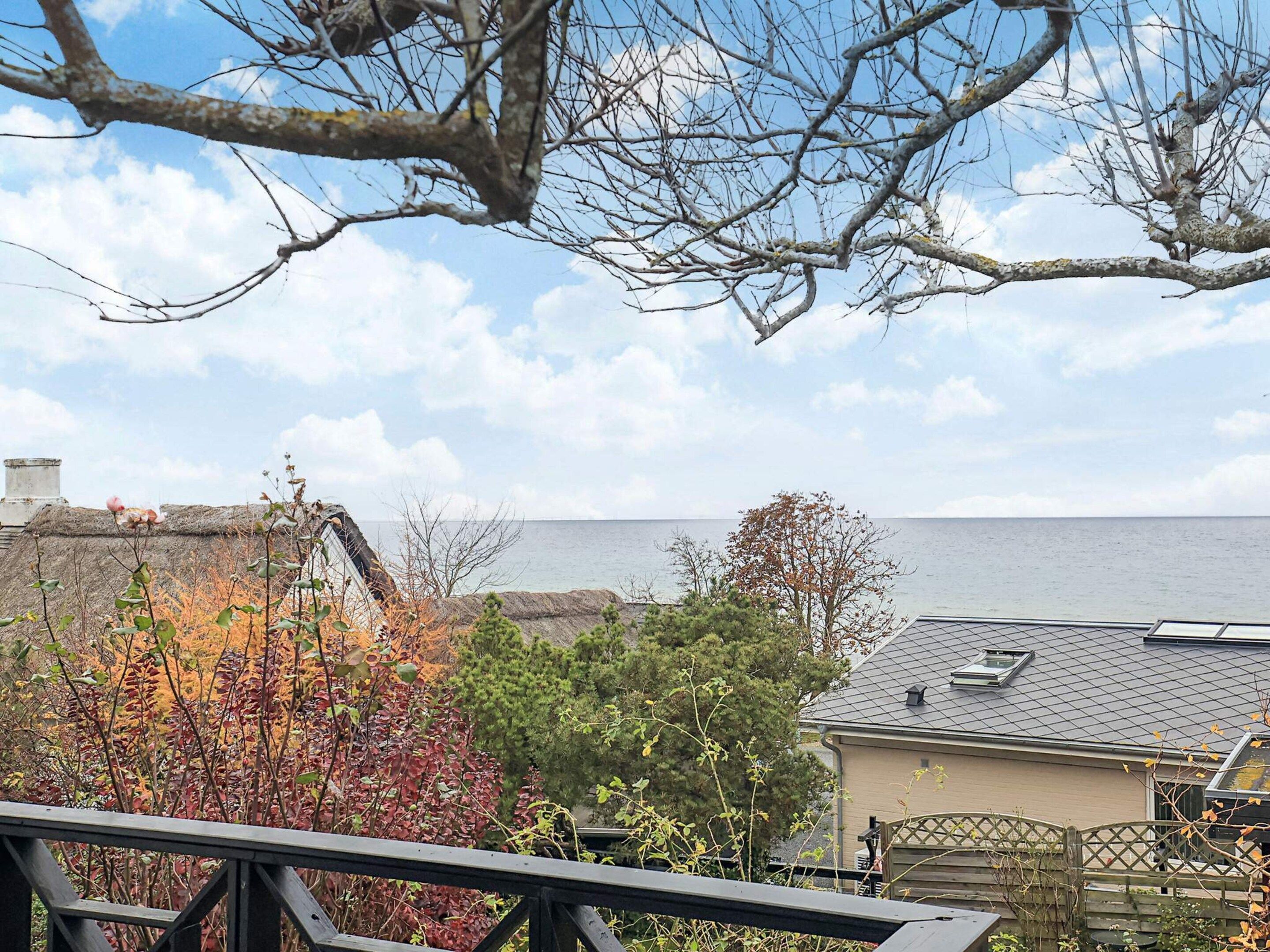 A coastal view with a house, a wooden deck, and a clear sky.