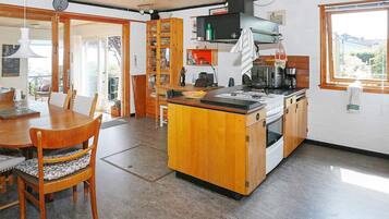 A kitchen with a central island, wooden cabinets, a stove, and a window.
