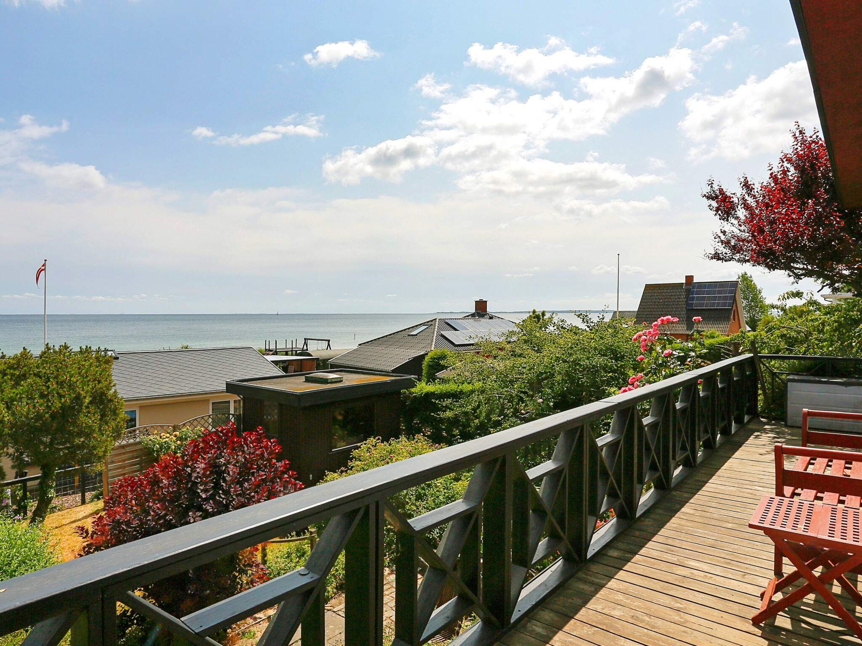 A wooden deck with a railing overlooking a residential area and a body of water.
