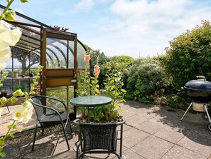 A patio with a table and chairs, a greenhouse, and a barbecue grill. - 5 Person Holiday Home in Hesselager (Hesselager)