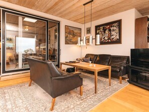Una sala moderna con un sofá de cuero, una mesa de centro de madera y un televisor.