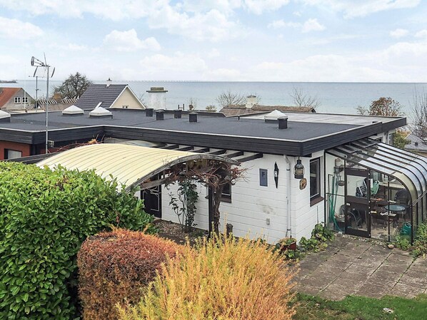 A modern house with a curved roof, a conservatory, and a view of the sea. - 5 Person Holiday Home in Hesselager (Hesselager)