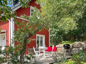 A red building with a deck area featuring outdoor seating and a barbecue grill. - 4 Person Holiday Home in Trensum (Trensum)