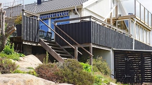 A modern house with a steep roof, a staircase leading to a deck, and a view of the surrounding landscape. - 4 Person Holiday Home in Kungshamn (Kungshamn)