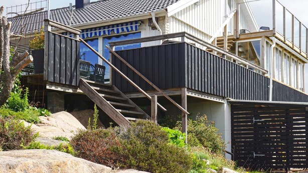 A modern house with a steep roof, a staircase leading to a deck, and a view of the surrounding landscape. - 4 Person Holiday Home in Kungshamn (Kungshamn)