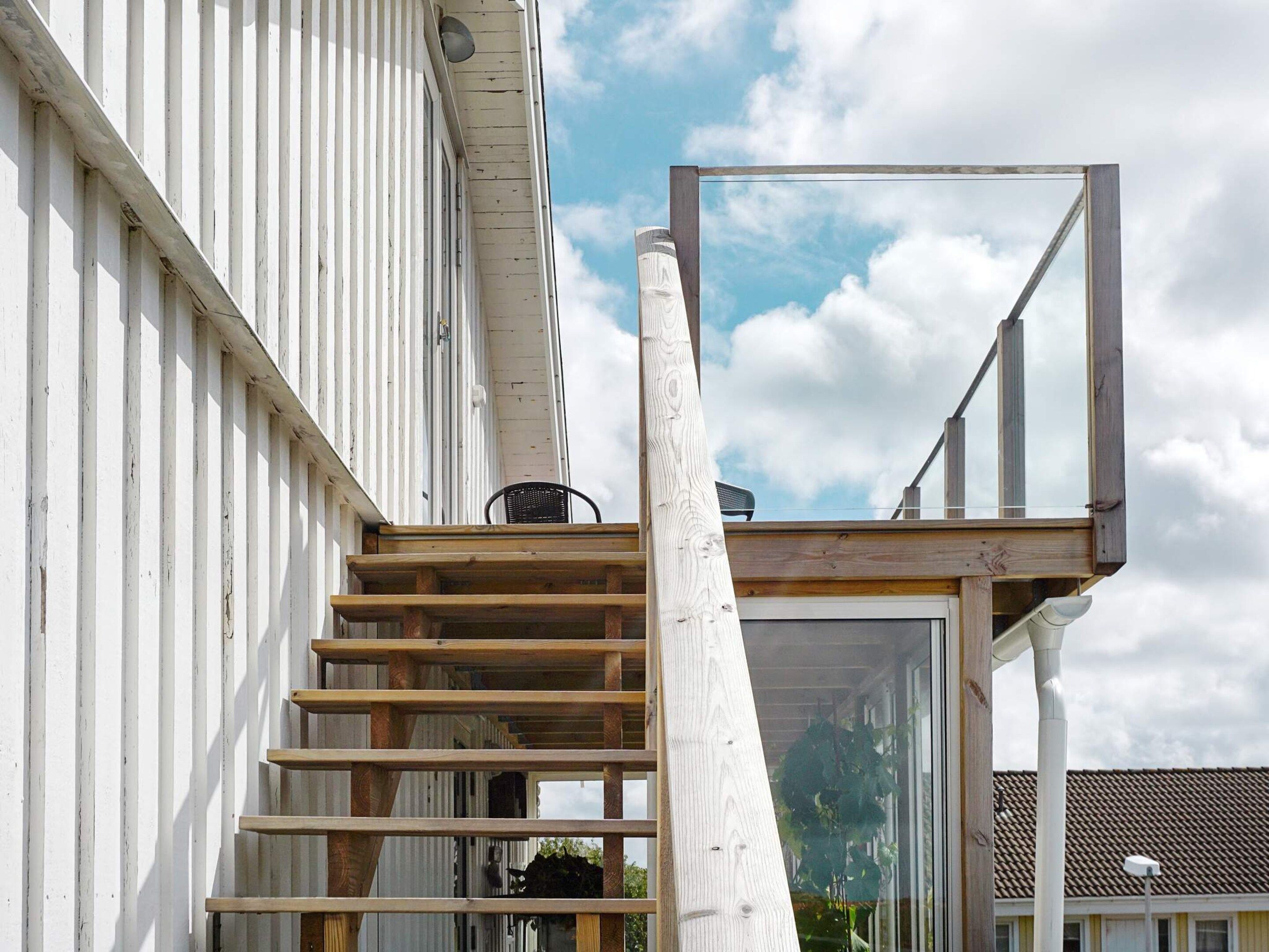 A wooden staircase leading to a balcony with a metal frame structure.