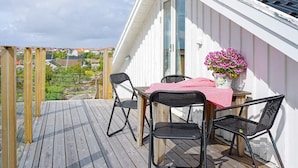 A balcony with a table and chairs, a potted plant, and a view of a residential area. - 4 Person Holiday Home in Kungshamn (Kungshamn)