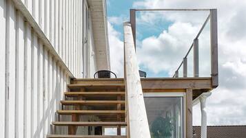 Una escalera conduce a un balcón con vistas a una zona residencial.